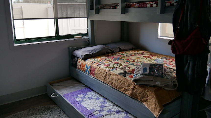 A double bed with a single bed bunk and trundle with colorful blankets on top.  