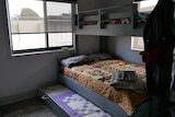 A double bed with a single bed bunk and trundle with colorful blankets on top.  