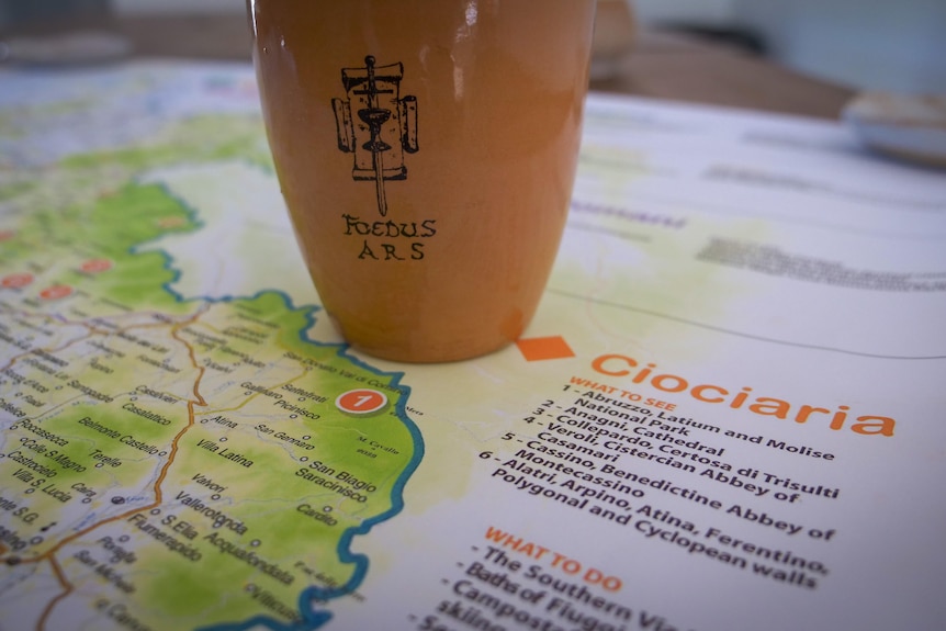 A terracotta cup on a map of Italy.