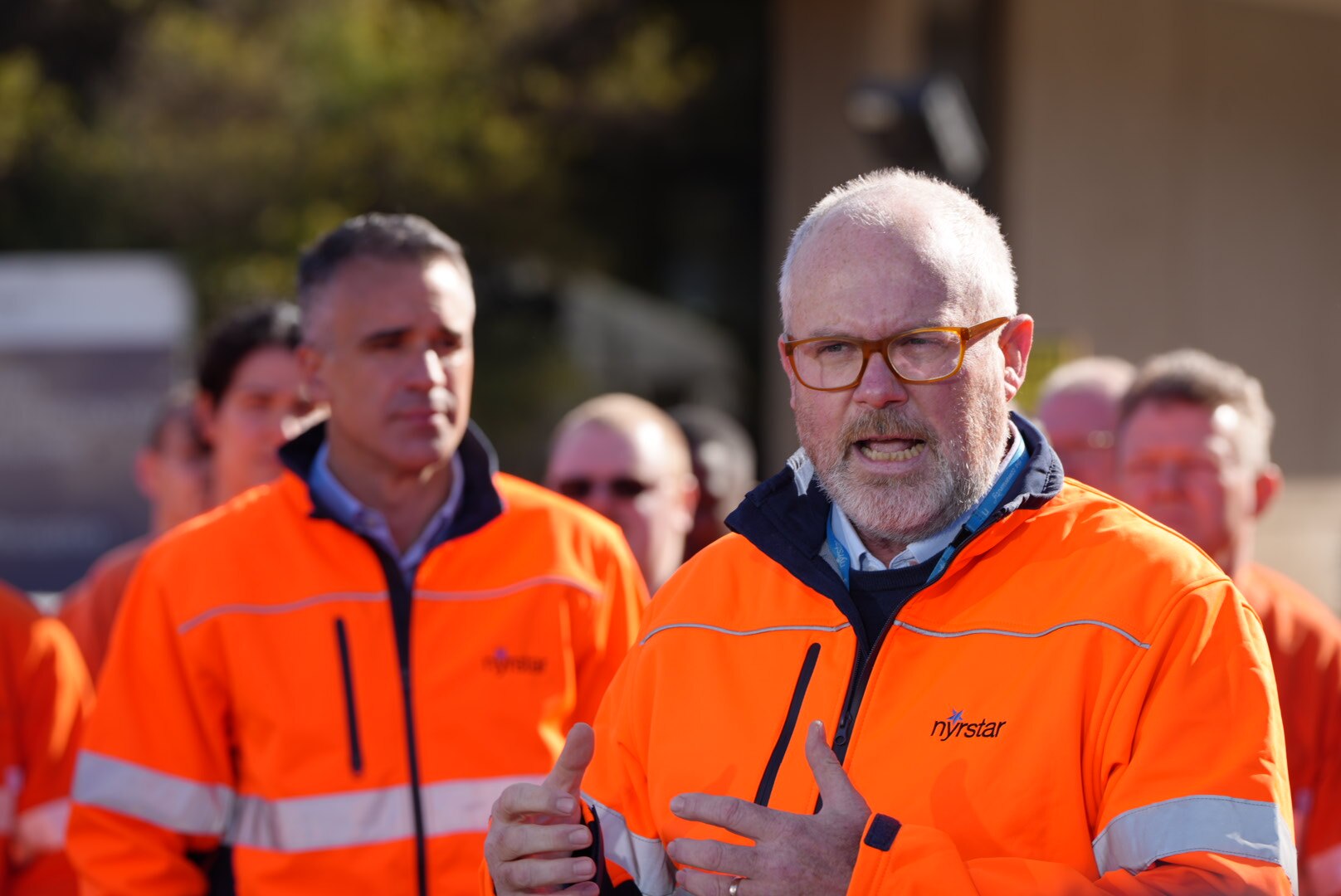 Politicians in hi-vis vests at an industrial site.