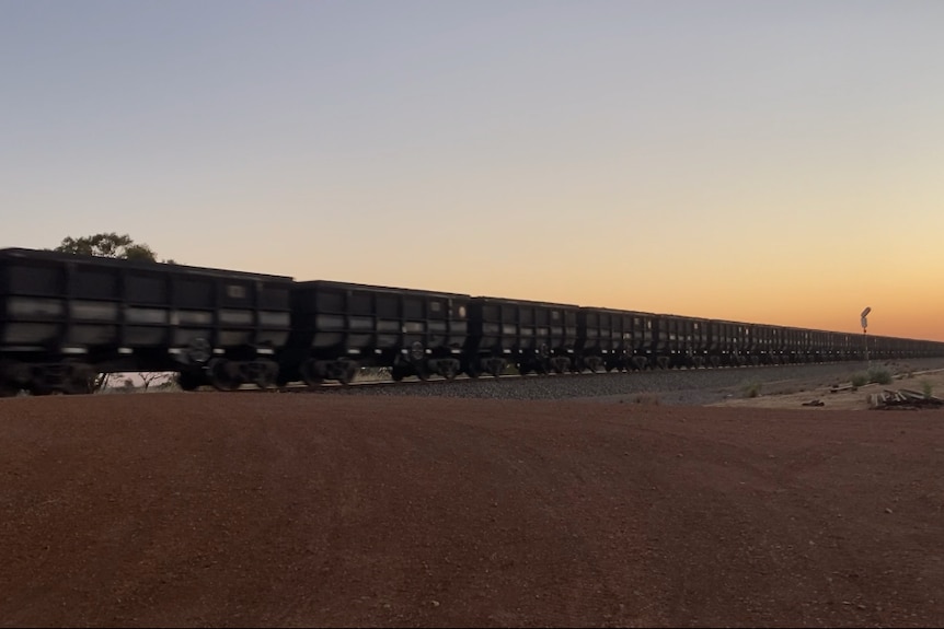 photo of rail wagons on sunset which are black with no lighting on them. 
