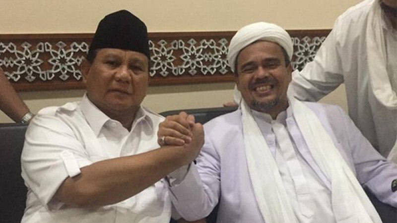 Hardline Indonesian cleric Rizieq Shihab (pictured right) smiles at the camera