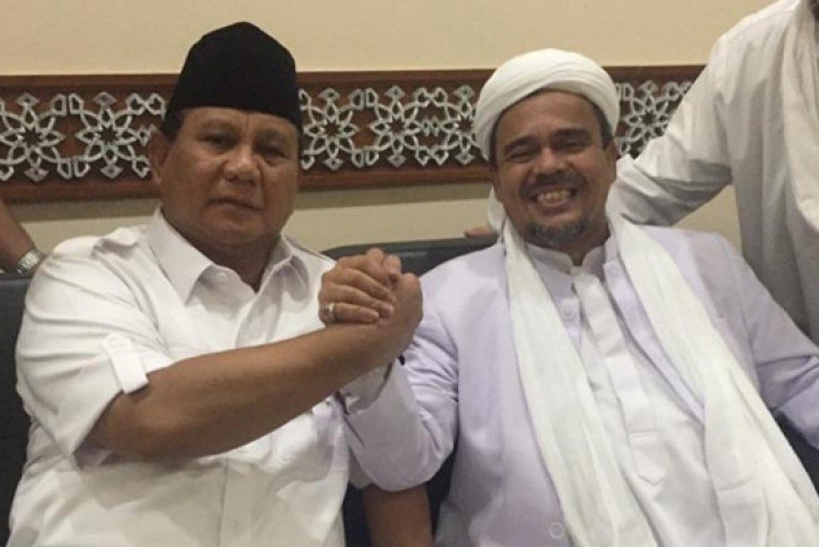 Hardline Indonesian cleric Rizieq Shihab (pictured right) smiles at the camera