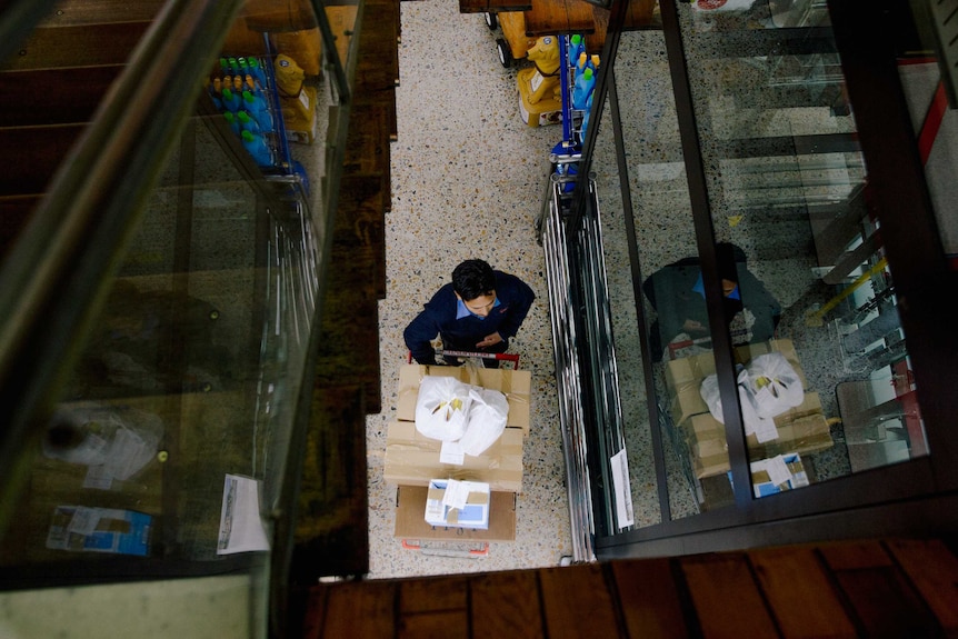 A store worker pushes a trolley full of stock.