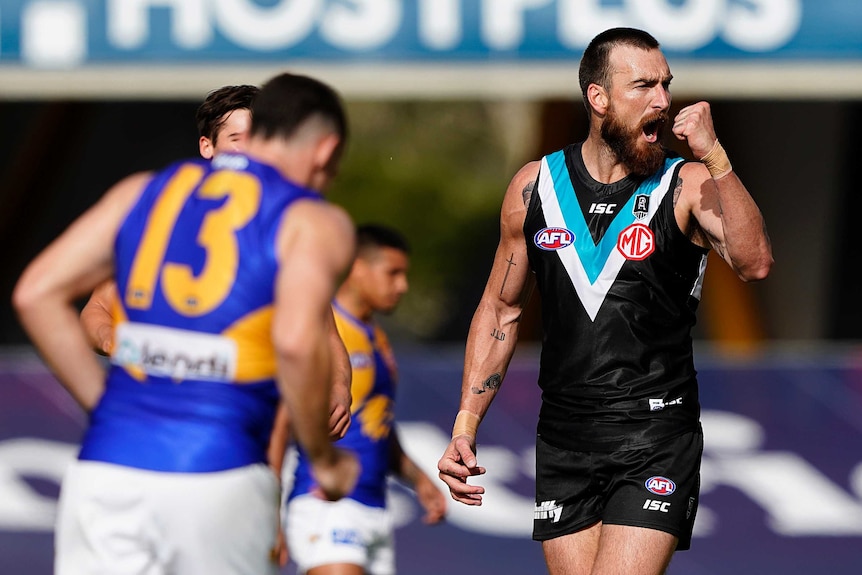 A Port Adelaide AFL player pumps his left fist as he celebrates kicking a goal against West Coast.