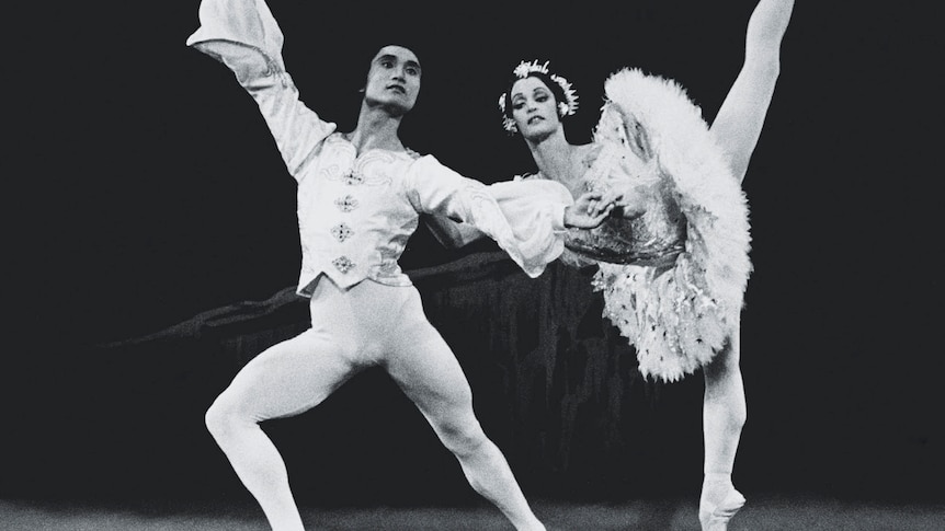 A male and a female ballet dancer strike a pose on stage