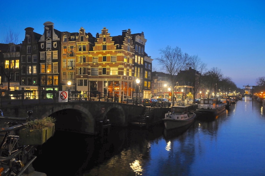 A canal in Amsterdam with buildings lit up