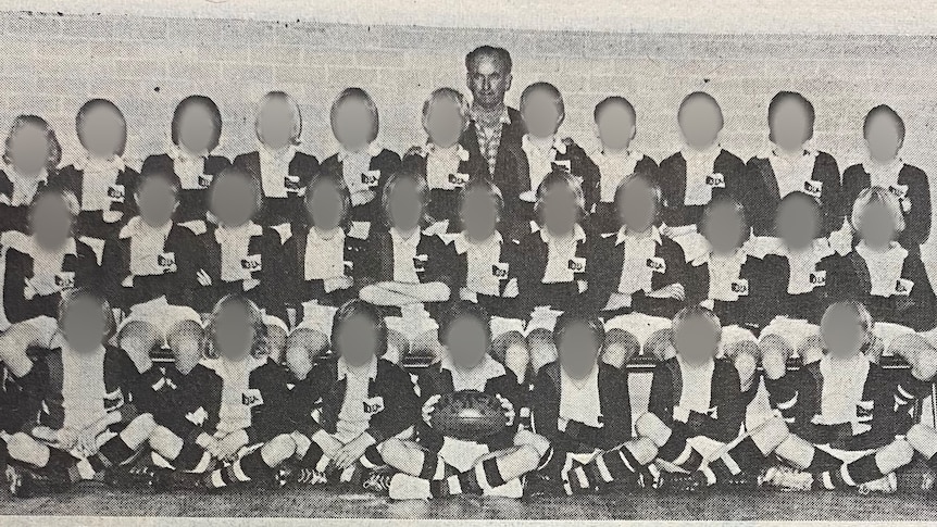 A large group of boys in Australian rules strips pose for a photo with their coach.