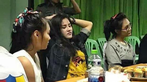 Preeyanuch "Preaw" Nonwangchai (centre) and two alleged accomplices sit at a table after turning themselves in.