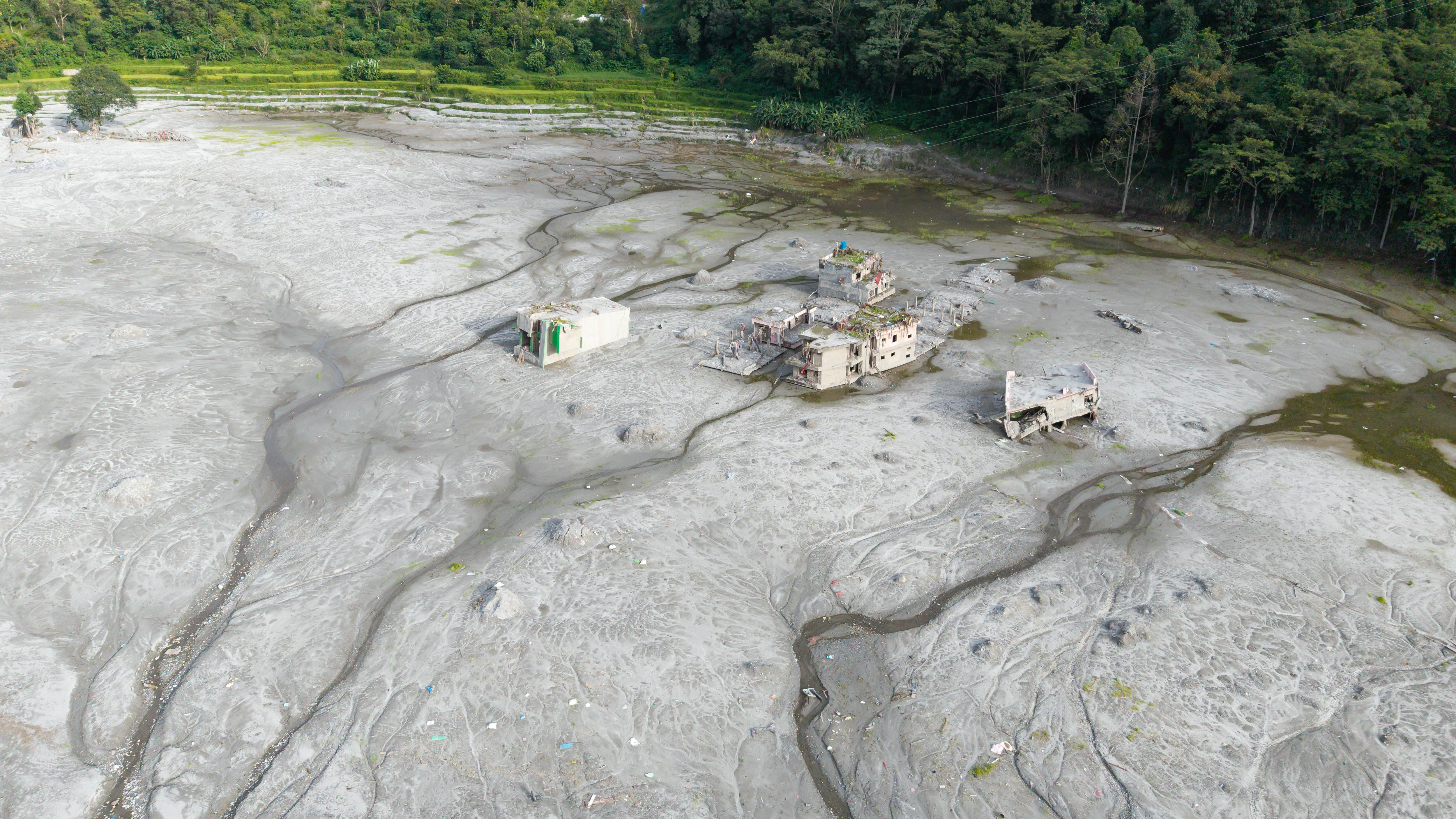 In a sprawling field of mud, two lone buildings stand.