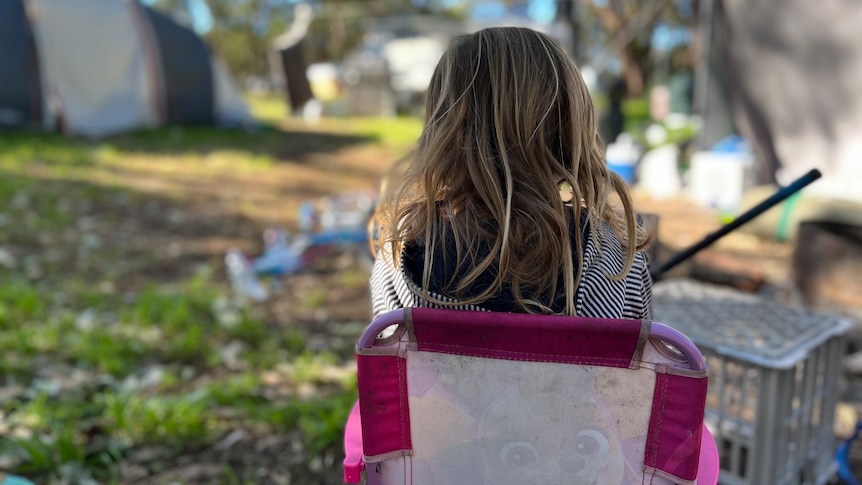 Back of little girl sitting on chair in a campground