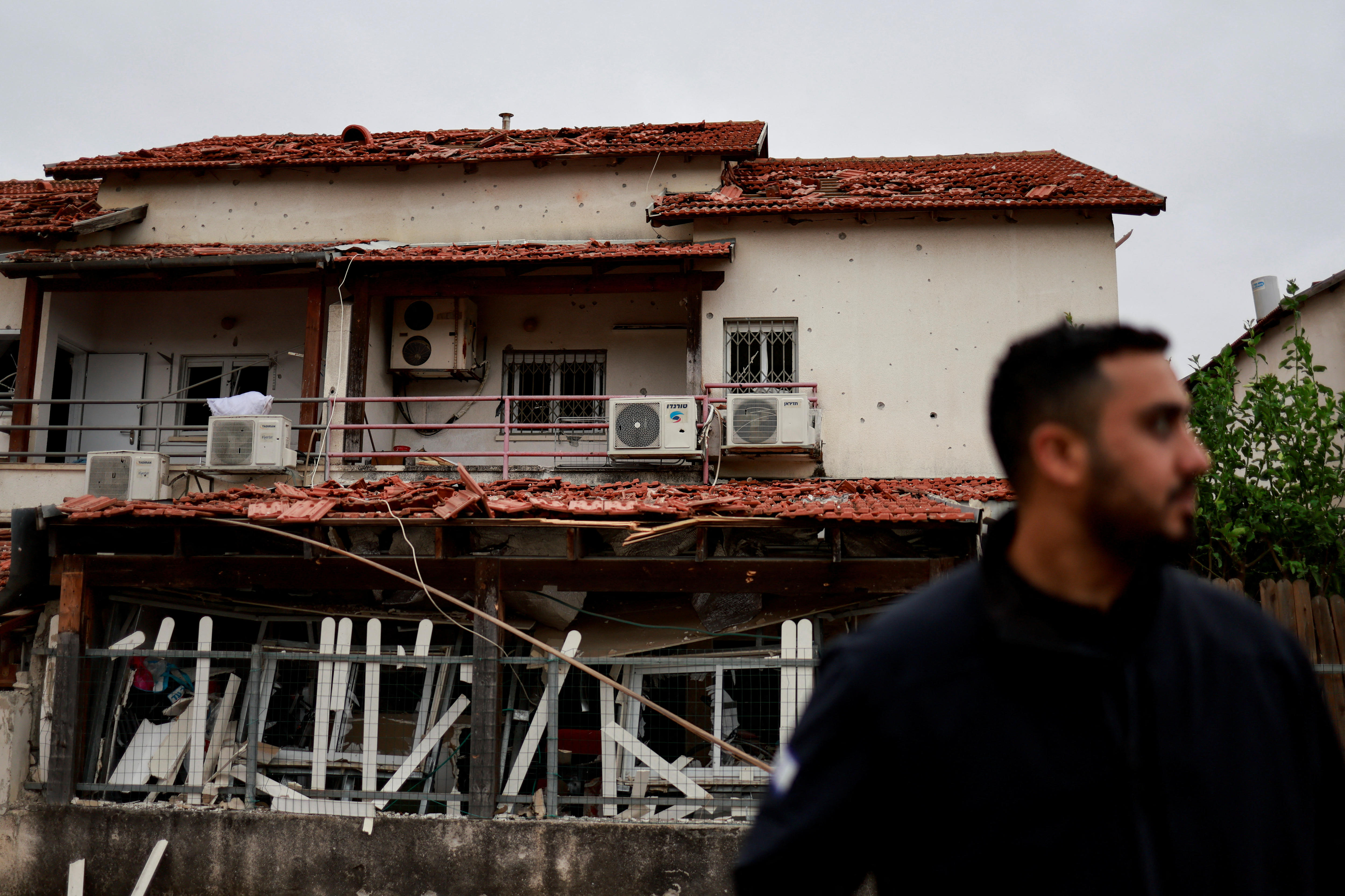 A man in front of a ruined house. 