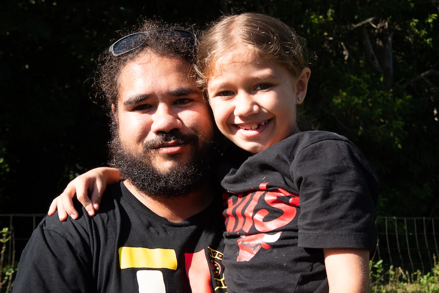 Aboriginal man holds his young daughter