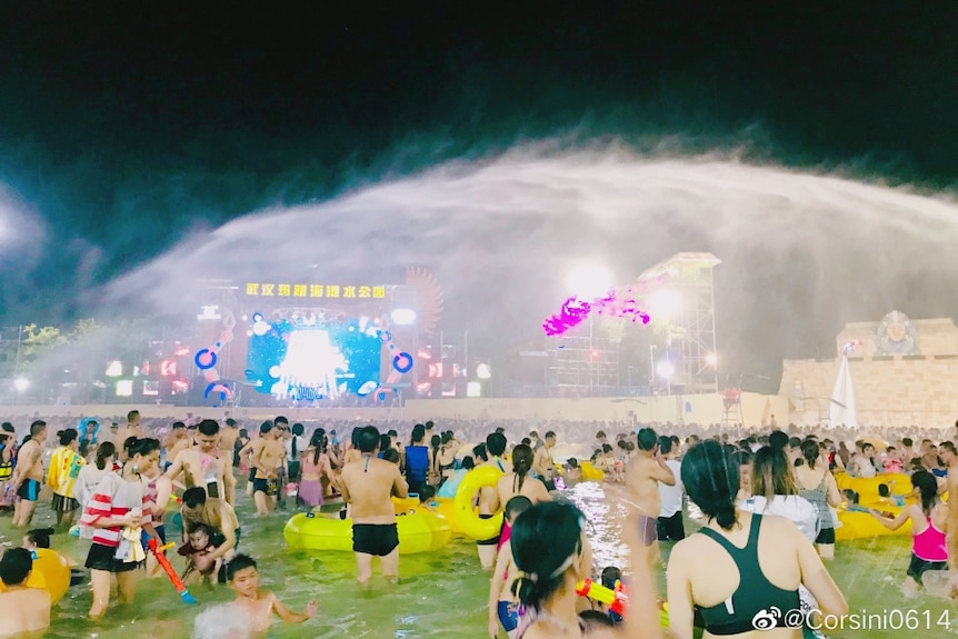 People with pool cushions hang out in the water as more water is sprayed over them at a music festival in Wuhan.