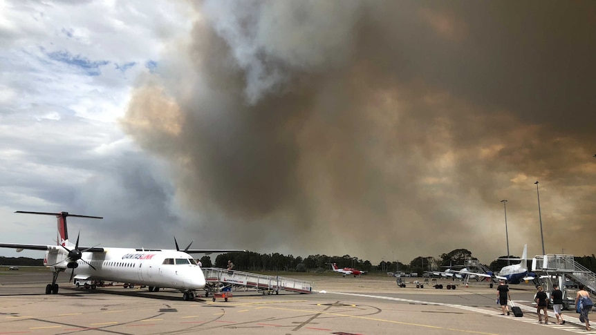 Plain in front of a big plume of smoke.