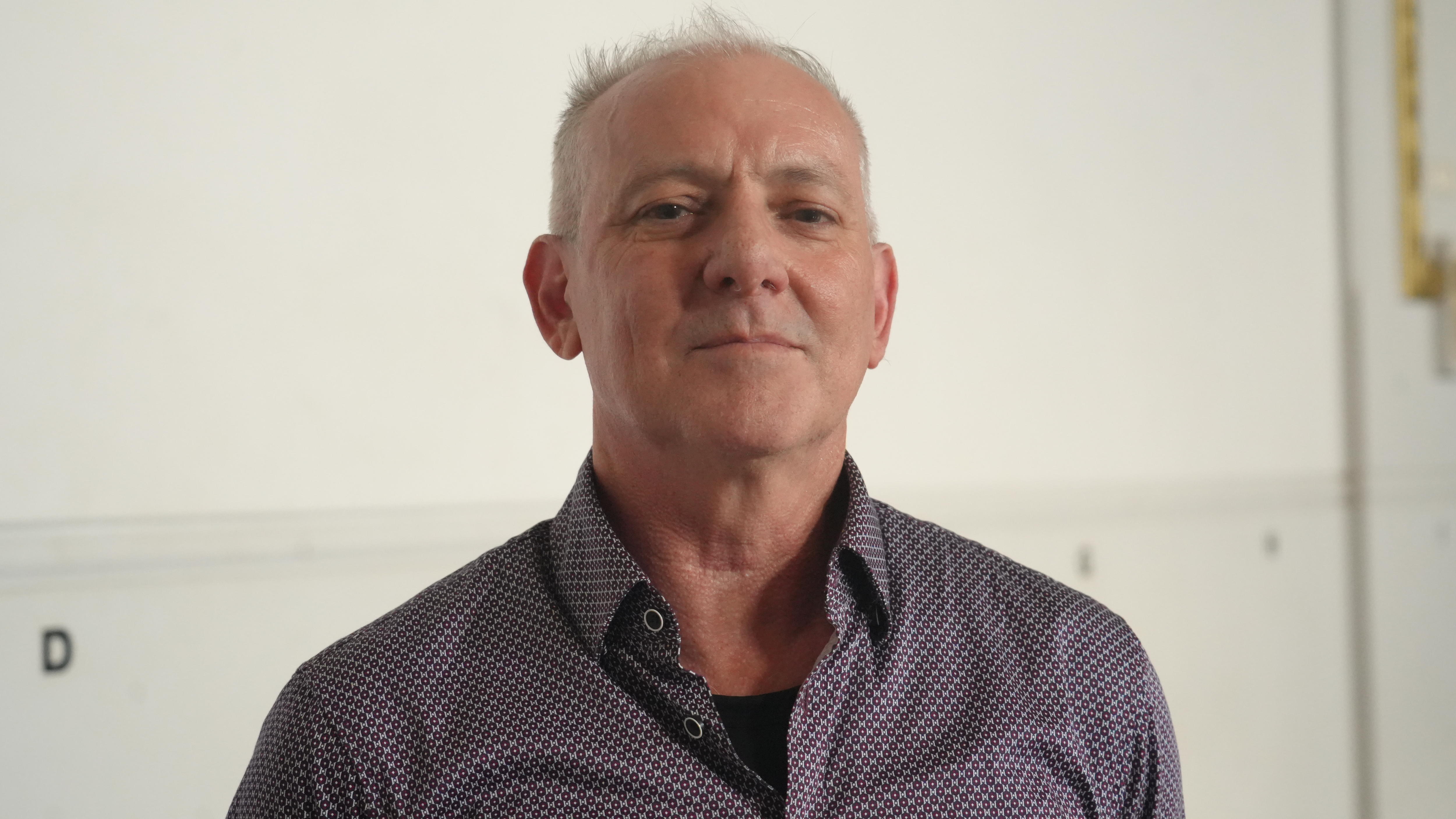 A close-up of a man looking at the camera with a neutral expression.