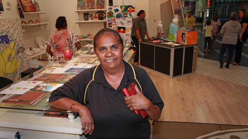 Patricia Corrie smiling surrounded by Indigenous art work in a shop in Mackay