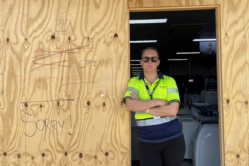 woman leans against a door, with sunnies on 