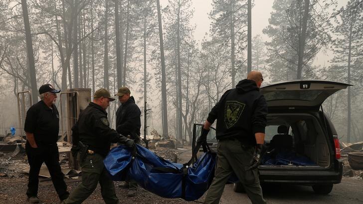 Four Yuba and Butte County Sherriff deputies carry a body bag to a car in the wake of wildfires in Paradise, California