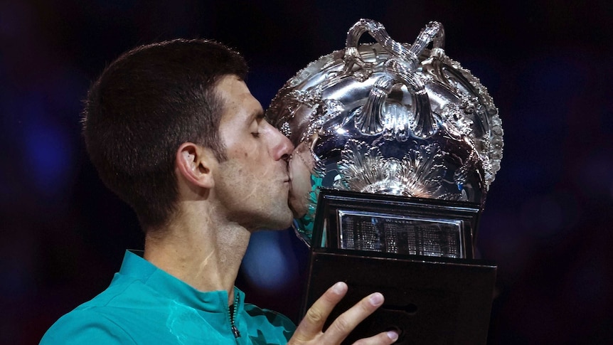 Tennis player celebrates victory with his trophy.