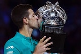 Tennis player celebrates victory with his trophy.