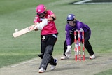 A WBBL batter with her head down swings through the ball as the wicketkeeper watches from behind the stumps.