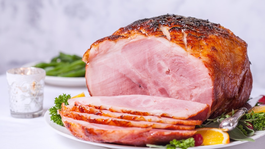 A glazed Christmas ham sitting on a table.