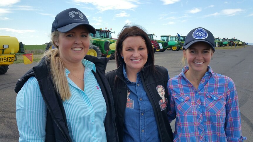 Senator Jacqui Lambe posing with farmers mine protestors Sarah Hubbar and Maddy Coleman with a line of tractors behind them.