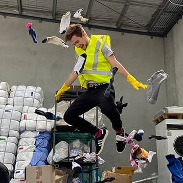 A man in a high-vis vest jumps into the air surrounded by socks.