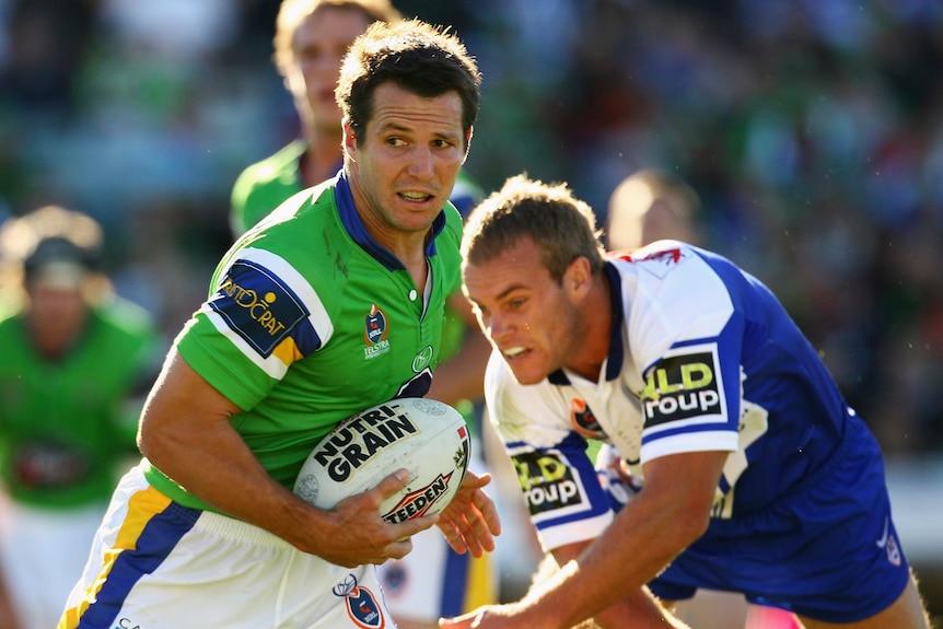 A man evades a defender during a rugby league match