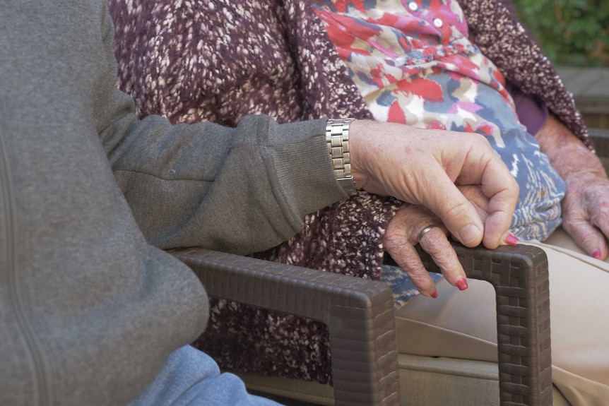 Ken holds Nancy's hand