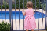 Young child standing at a backyard pool gate