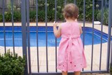 Young child standing at a backyard pool gate