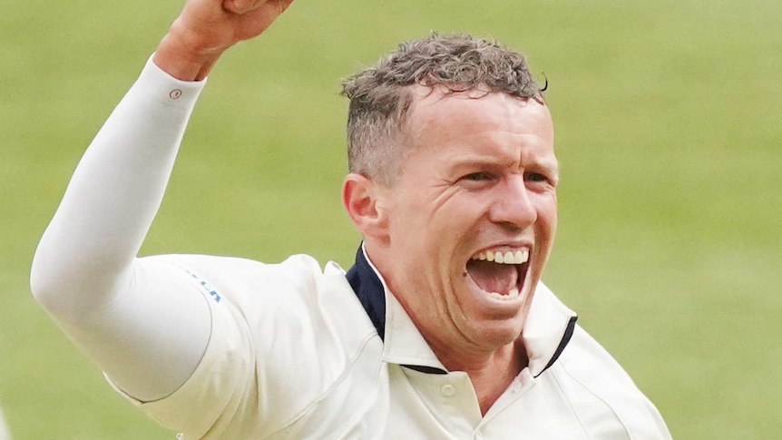 Peter Siddle raises his clenched fist and smiles wearing cricket whites