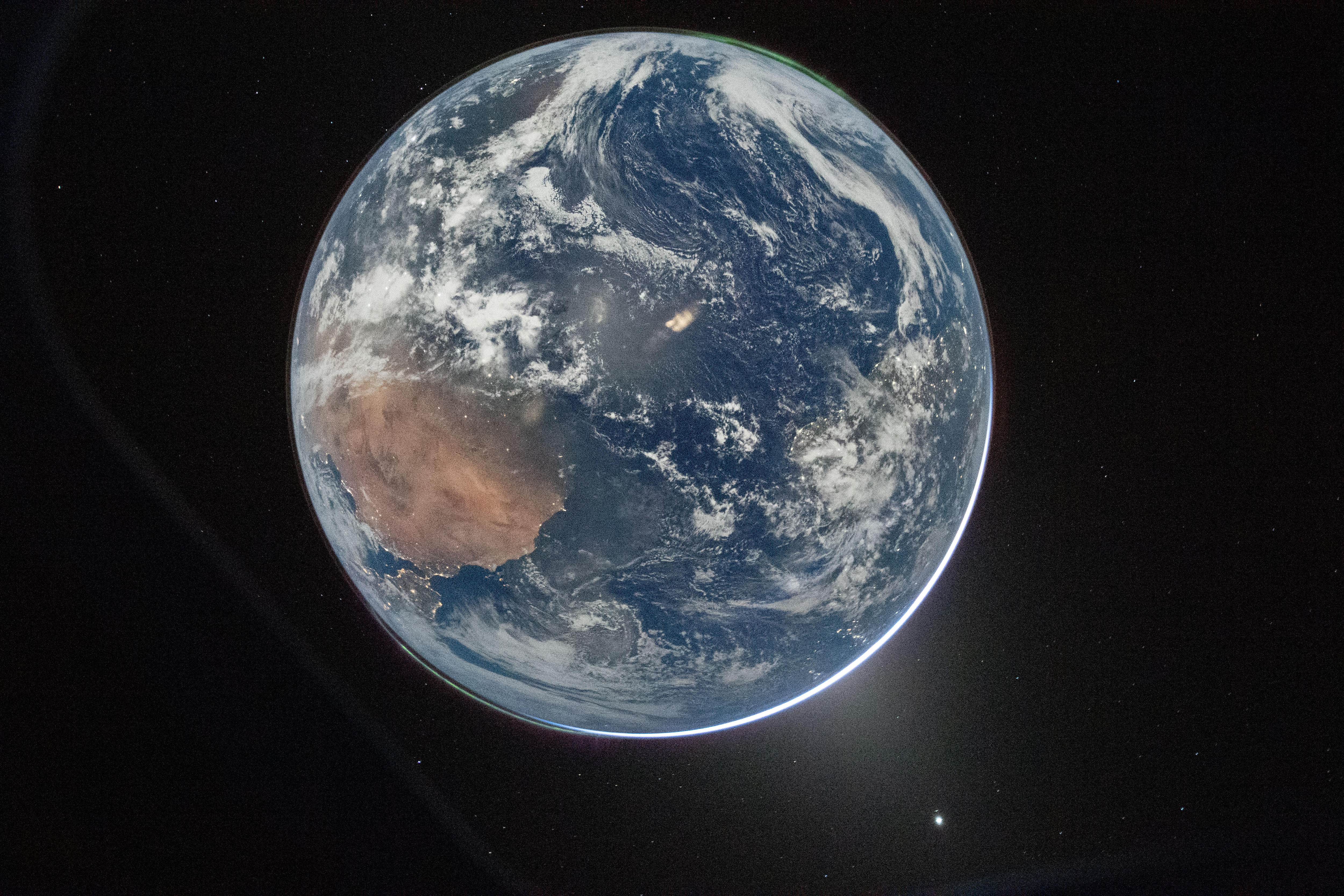 The entire Earth is seen from space, with blue oceans and swirling tendrils of white clouds. 