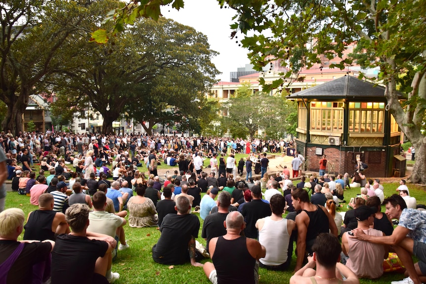 A large group of people sit in a park.