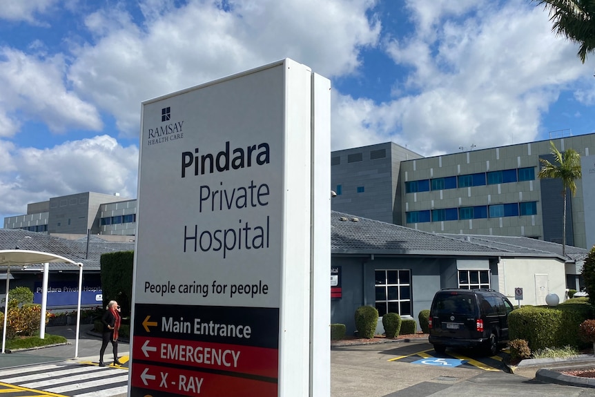 signage of hospital outside entry with person walking in background