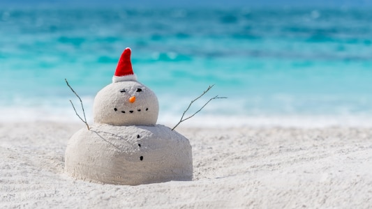Snowman made of sand wearing a Christmas hat