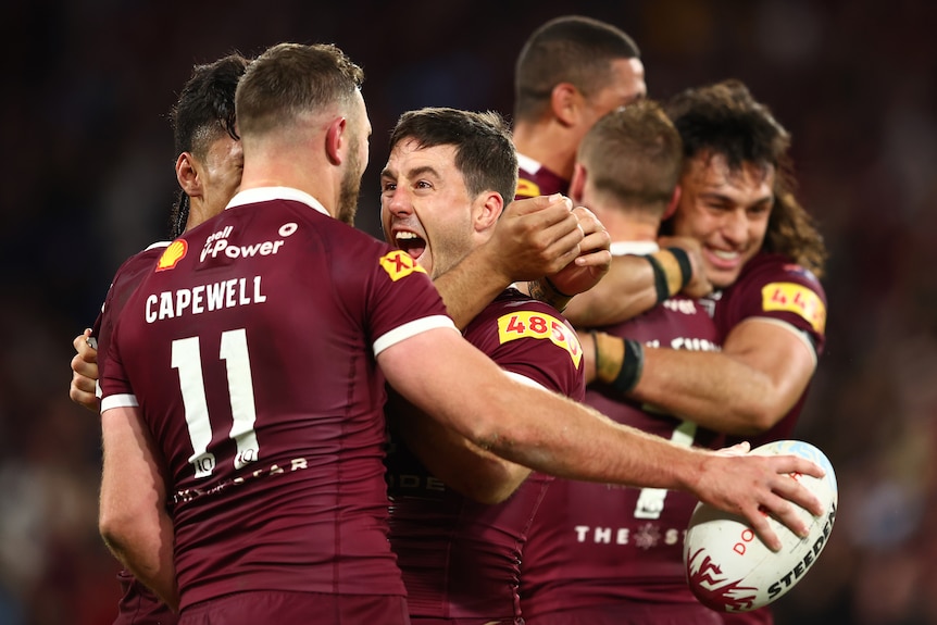 Queensland players embrace as they celebrate defeating NSW in State of Origin III.