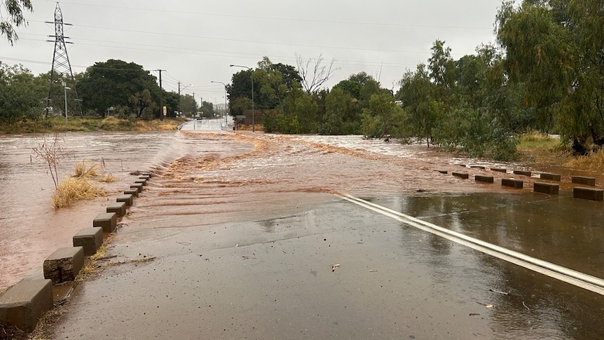 A river in Mount Isa floods a crossing, closing roads. 