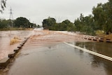 A river in Mount Isa floods a crossing, closing roads. 