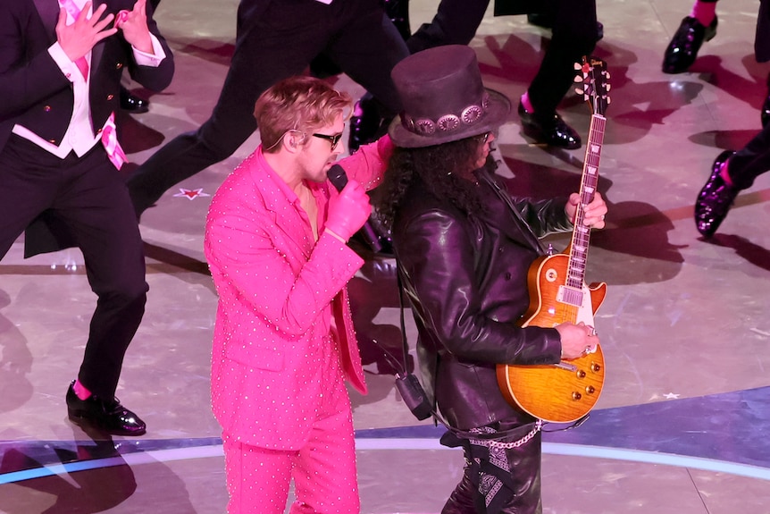 Ryan Gosling in pink next to Slash the guitarist. 