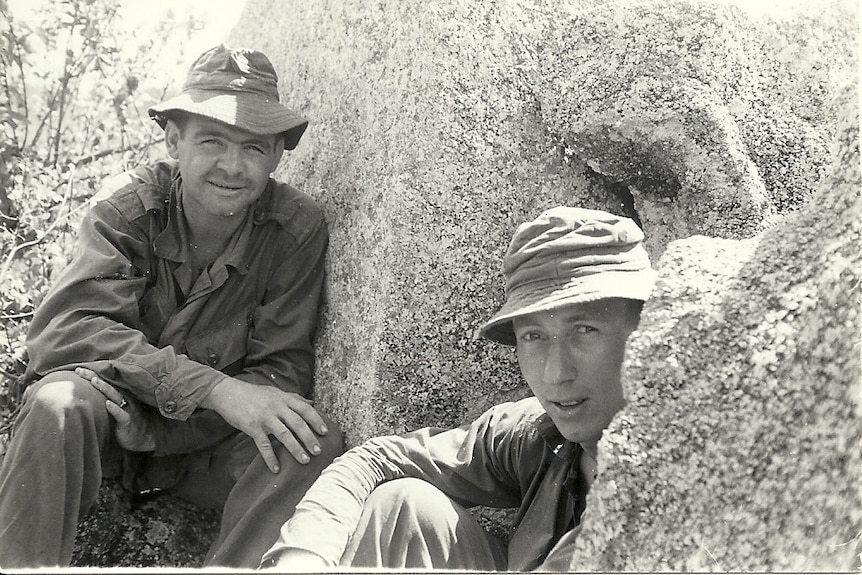 Laurie Drinkwater and Alan Parr sitting beside a rock.