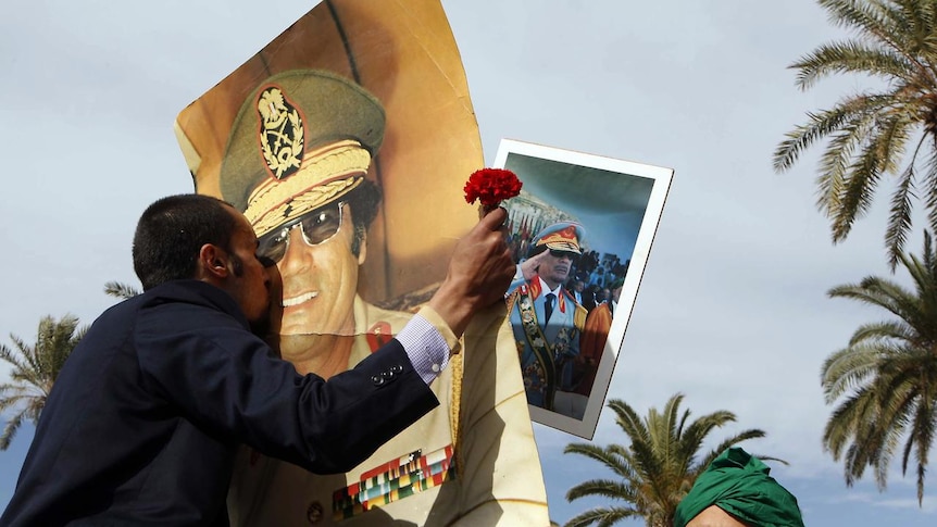 Libyan pro-government supporters kiss a portrait of leader Moamar Gaddafi