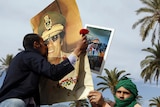 Libyan pro-government supporters kiss a portrait of leader Moamar Gaddafi