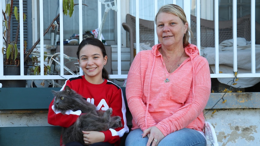 A mother and daughter holding a cat.