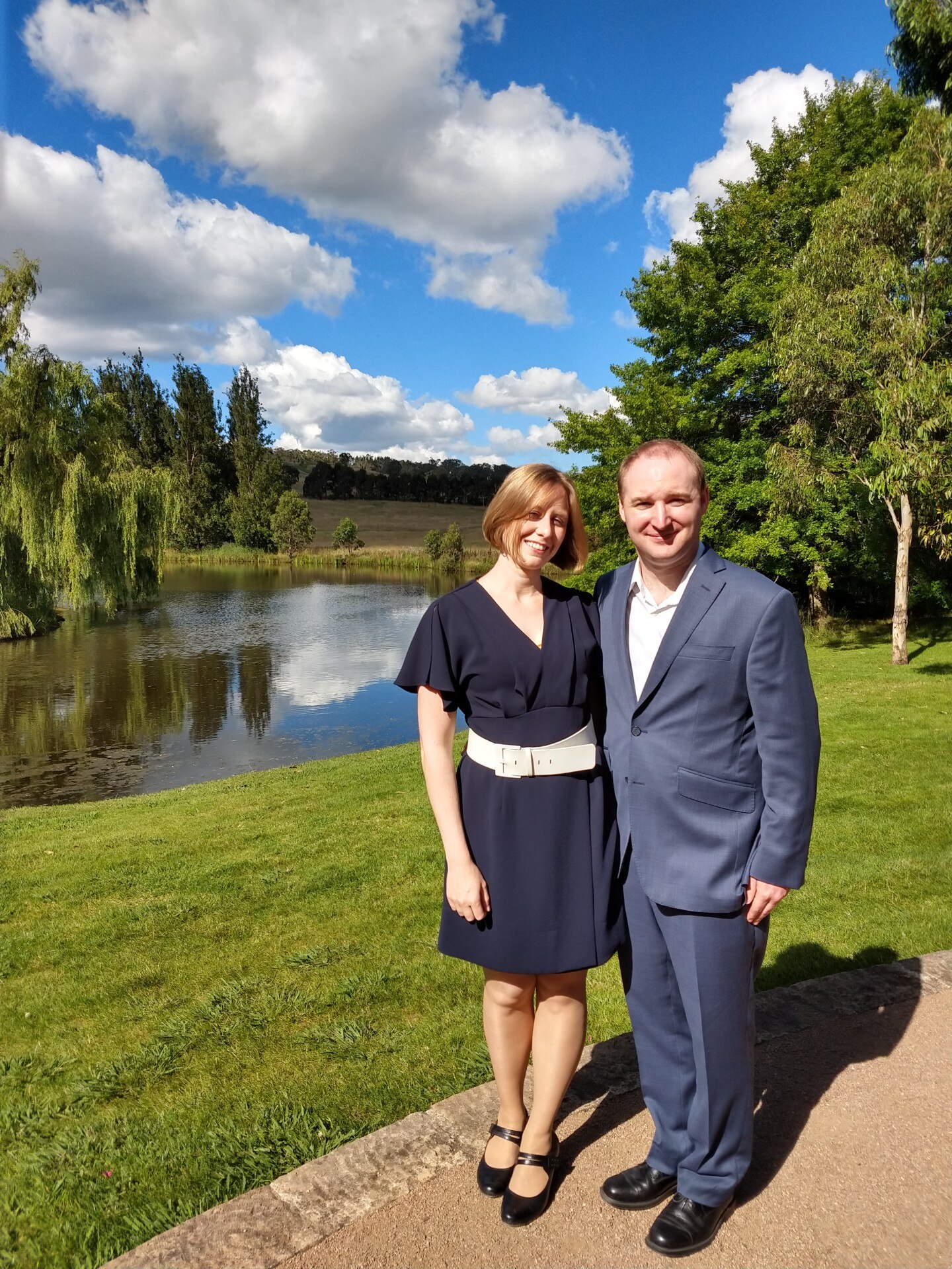A couple standing in front of a lake.