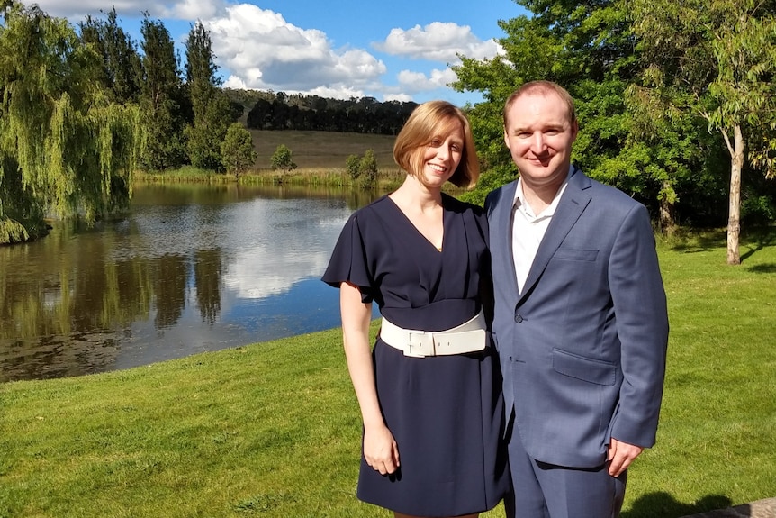 A couple standing in front of a lake.