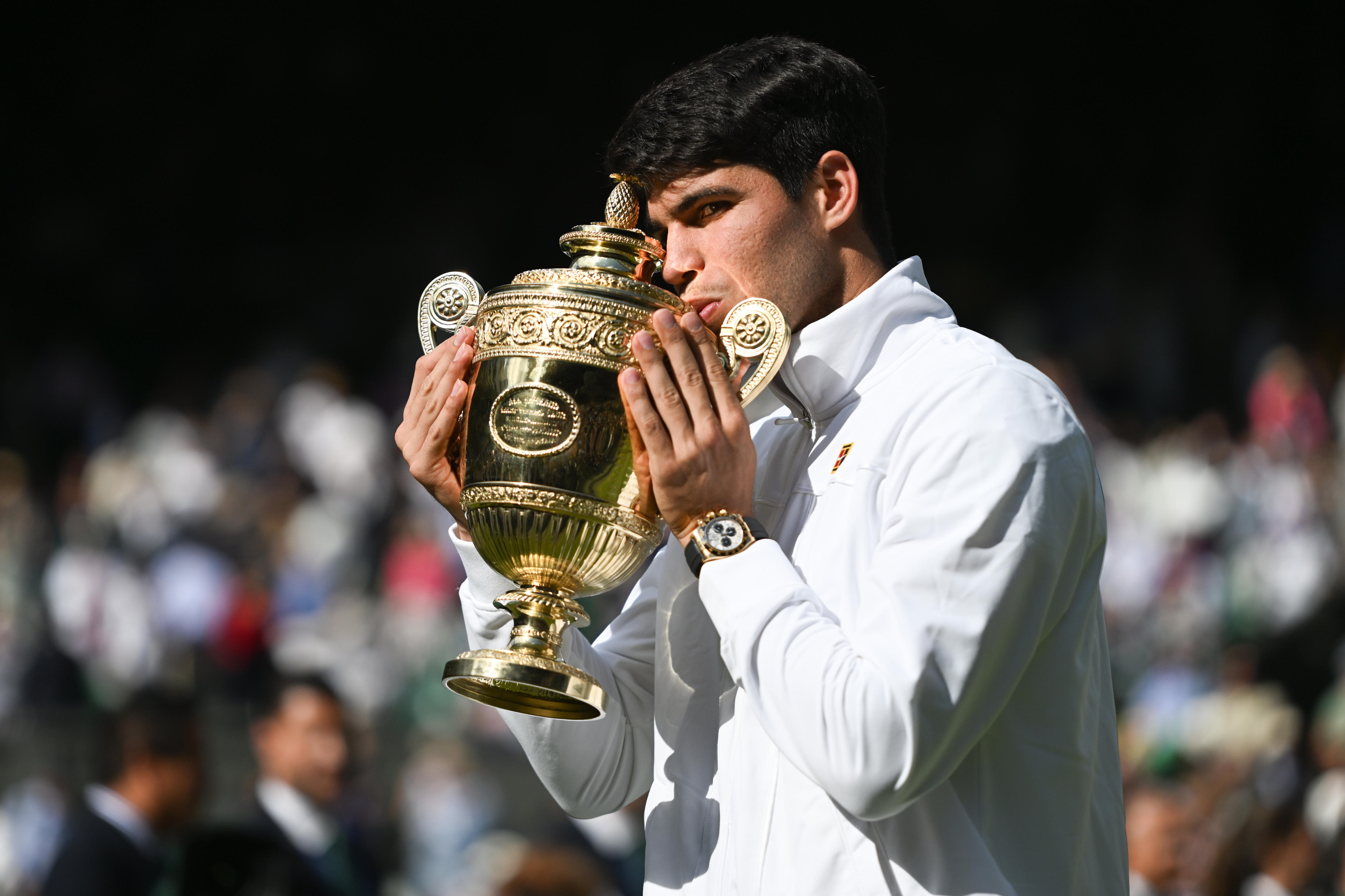 Carlos Alcaraz kisses the Wimbledon trophy.