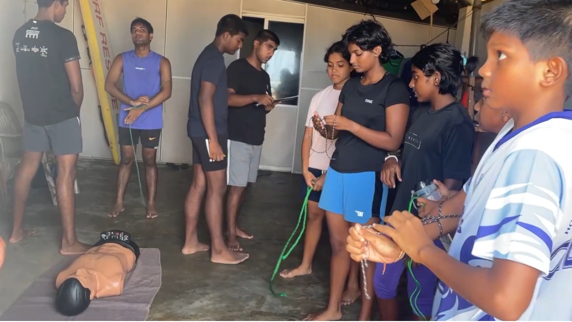 Meninos e meninas cercam uma múmia de plástico.